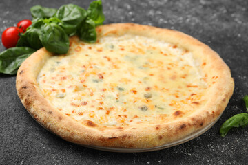 Delicious cheese pizza, basil and tomatoes on black textured table, closeup
