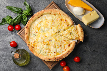 Delicious cheese pizza and ingredients on dark grey table, flat lay