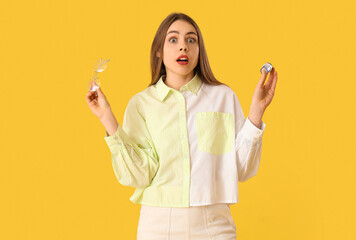 Shocked young woman with eyeglasses on yellow background