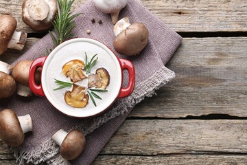 Delicious homemade mushroom soup in ceramic pot and fresh ingredients on wooden table, flat lay. Space for text