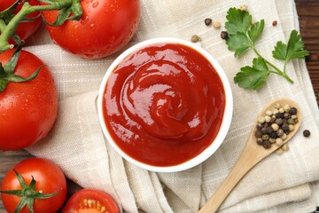Delicious ketchup in bowl, tomatoes, parsley and peppercorns on table, top view