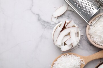 Coconut flakes, pieces, spoon and grater on white marble table, flat lay. Space for text