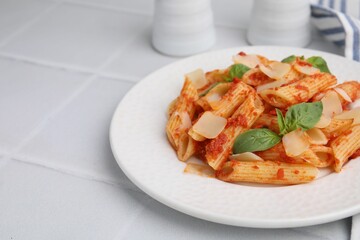 Tasty pasta with tomato sauce, cheese and basil on white tiled table