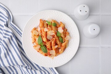 Tasty pasta with tomato sauce, cheese and basil on white tiled table, top view