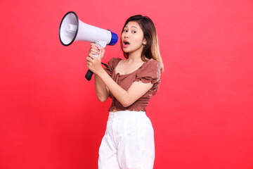 The expression of an elegant Asian woman shouting with both hands holding an audio megaphone...