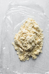 Overhead view of yogurt scones dough on plastic wrap, Raw scone dough on a parchment lined baking sheet, process of making scones