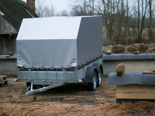Metal covered small size trailer for towing by car or truck parked in a rural country side,...
