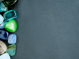 Colorful gems of different size and shape on a dark empty background for message. Design mock up. Natural materials decoration.