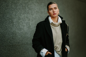 Portrait of a stylish woman with piercings wearing coat on a city street