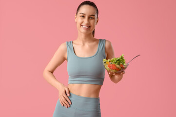 Beautiful young happy woman with bowl of fresh salad on pink background. Weight loss concept
