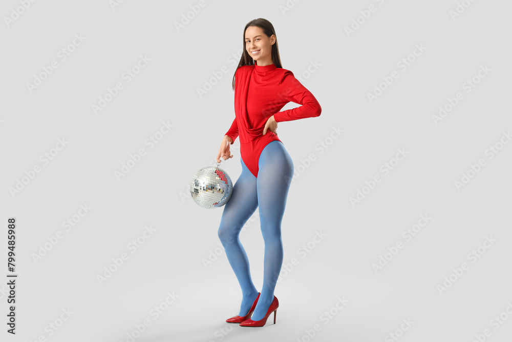 Poster Happy young fashionable woman with disco ball on grey background