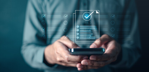 quality, management, check, compliance, list, marketing, information, social, network, system. A man is holding a smartphone with a check mark on it. Concept of accomplishment or satisfaction.