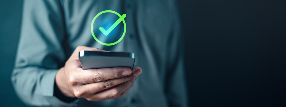 checkmark, confirm, accept, check, complete, marketing, tick, information, mark, checklist. A man is holding a smartphone with a check mark. Concept of approval or satisfaction.
