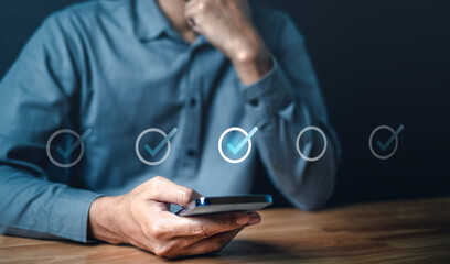 social, marketing, touch, information, corporate, network, office, finance, smartphone, media. A man is holding smartphone and looking at a screen with check mark. as like completed or approved.