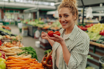 Customer buying fresh tomato at farmers market and smiling at camera