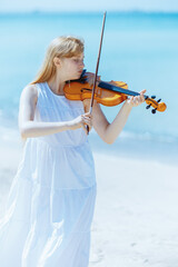 modern girl in white dress on ocean coast enjoying playing