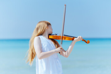 teenage girl in dress on ocean coast enjoying playing