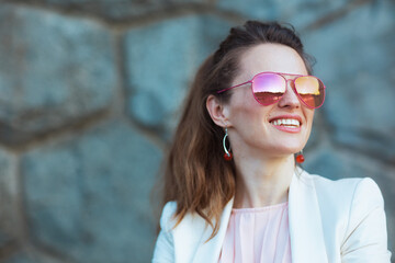 happy elegant woman in pink dress and white jacket in city