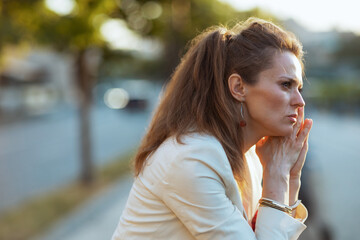 pensive woman in dress and jacket in city looking into distance