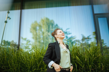happy modern woman worker near office building in black jacket