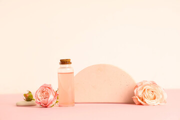 Bottle of cosmetic oil, roses and plaster stand on pink background