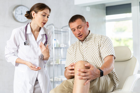 Man patient shows doctor sore knee and tells story of injury to woman doctor, complaints about well-being. Sports and household joint injury