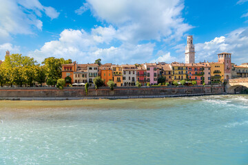 View of colorful waterfront buildings in the medieval city of Verona, Italy, with the Cathedral Bell Tower rising above the historic old town along the River Adige.