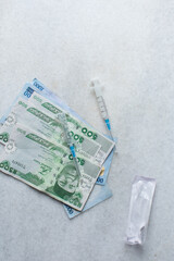 Syringe and medicine on naira notes, Concept photo show the rising cost of medicine in Nigeria