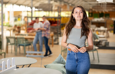 Girl buyer before buying furniture inspects table goods for defects and flaws. Customer in garden...