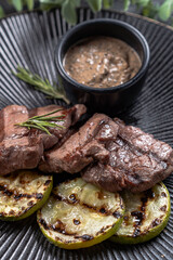 Fresh juicy delicious beef steak on a dark background. Meat dish with spices and herbs