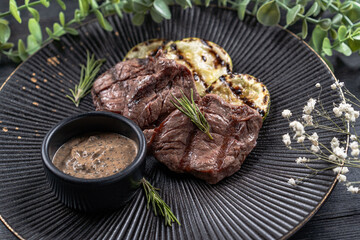 Fresh juicy delicious beef steak on a dark background. Meat dish with spices and herbs