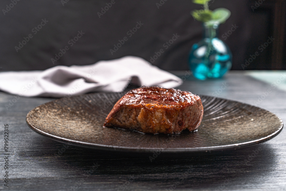 Wall mural Fresh juicy delicious beef steak on a dark background. Meat dish with spices and herbs