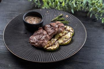 Fresh juicy delicious beef steak on a dark background. Meat dish with spices and herbs
