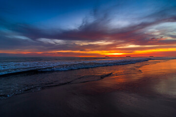 Fototapeta na wymiar Beautiful sunset over sandy beach with dramatic sky