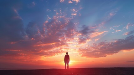 Silhouette of person standing against vibrant sunset sky with clouds