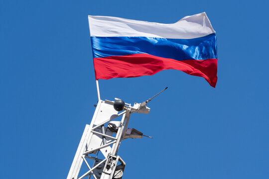 The national flag of the Russia mounted on top of a raised fire escape against the background of a blue sky on a sunny day. Holiday Firefighting Day of Russia, International Firefighters' Day IFFD