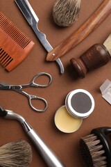 Moustache and beard styling tools on brown background, flat lay