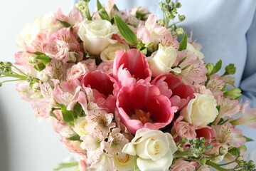 Woman with beautiful bouquet of fresh flowers on light background, closeup