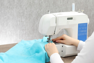 Seamstress working with sewing machine at table indoors, closeup