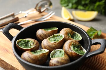 Delicious cooked snails in baking dish on table, closeup