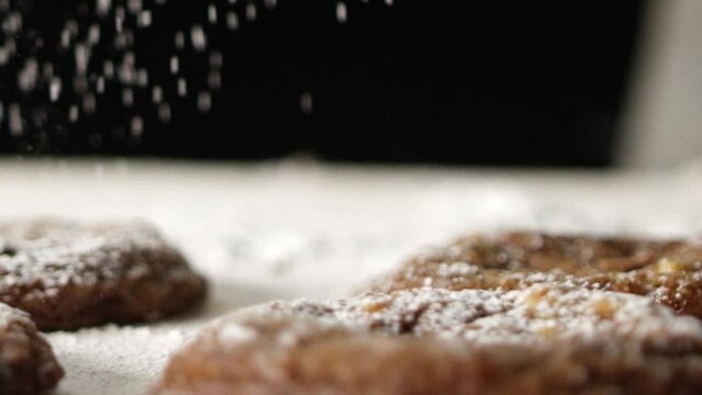 Powdered sugar sifted onto cookies on counter surface