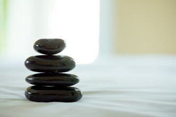 Balanced perfectly in a spa environment, a stack of smooth black stones creates tranquil atmosphere, enhancing the sense of focus and relaxation
