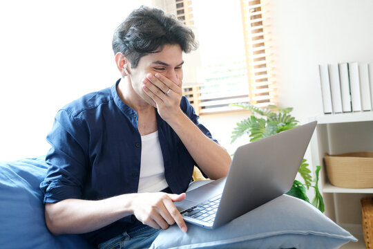 Young man surprising while looking at laptop computer, work at home