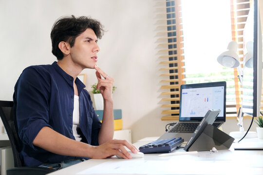 Young man thinking while working with computer at home office, wrok from home