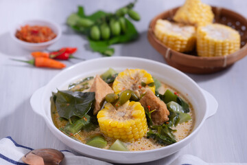 Sayur Lodeh is a vegetable dish made with coconut milk that is typical of Indonesia, especially in Central Java and DI Yogyakarta. Served in a bowl on a white table. Selective focus.