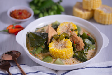 Sayur Lodeh is a vegetable dish made with coconut milk that is typical of Indonesia, especially in Central Java and DI Yogyakarta. Served in a bowl on a white table. Selective focus.