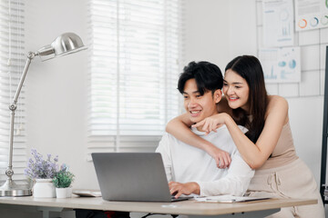 Cheerful young man and woman reviewing content on a laptop in a bright contemporary office setting.