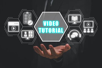 Video tutorial concept, Businessman hand holding video tutorial icon on virtual screen.