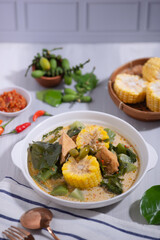 Sayur Lodeh is a vegetable dish made with coconut milk that is typical of Indonesia, especially in Central Java and DI Yogyakarta. Served in a bowl on a white table. Selective focus.