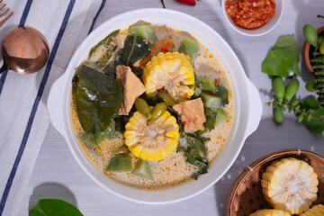 Sayur Lodeh is a vegetable dish made with coconut milk that is typical of Indonesia, especially in Central Java and DI Yogyakarta. Served in a bowl on a white table. Selective focus.